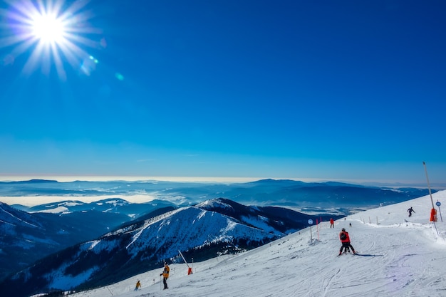 Winters slowakije. skigebied jasna. panoramisch uitzicht vanaf de top van de met sneeuw bedekte bergen en skipiste met skiërs