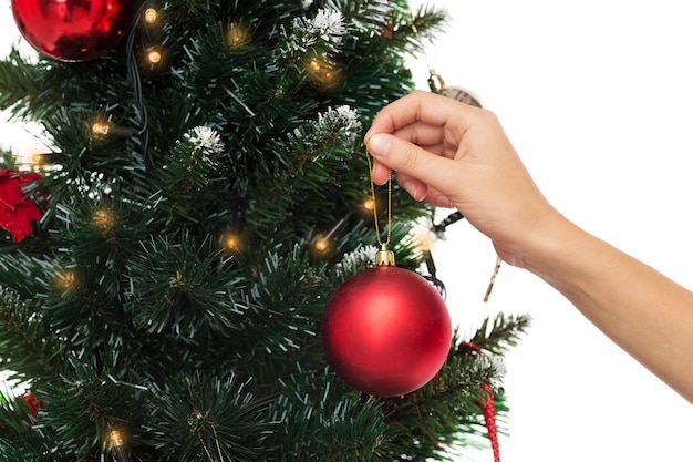 Wintervakantie, feest en mensenconcept - close-up van een vrouw die de kerstboom decoreert met bal