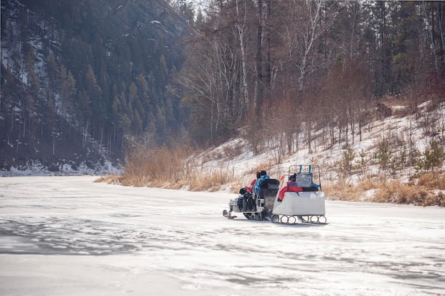 Foto winterwandeling met familie op een sneeuwscooter op een bevroren rivier een sneeuwscooter met aanhanger rolt kinderen