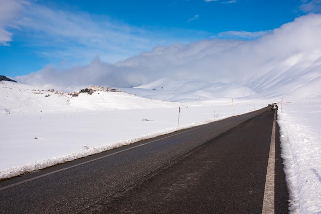 Winterweg in een vallei omgeven door bergen bedekt met sneeuw