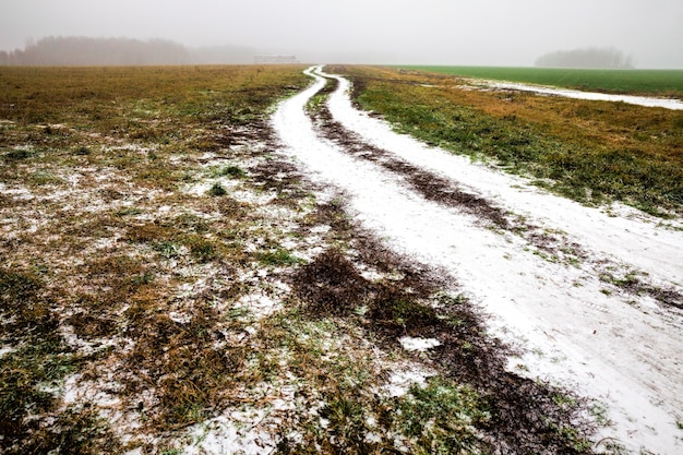 Winterweg met sporen van auto's in de winter, bedekt met sneeuw na sneeuwval, sporen van auto's op de weg in het veld