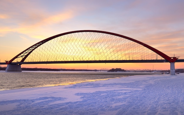 Winterzonsopgang op de rivier de Ob. Bugrinsky autobrug op de bevroren sneeuwbank in Novosibirsk