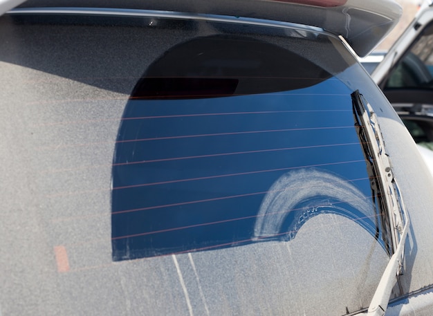 Wiper cleans a dirty rear window of a car