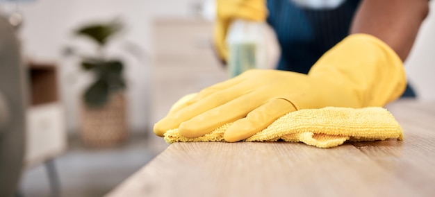 Wiping cloth and hands of a man on a table cleaning the dust with gloves in a house Bacteria service and cleaner with product to clean for disinfection of a surface desk or apartment for health