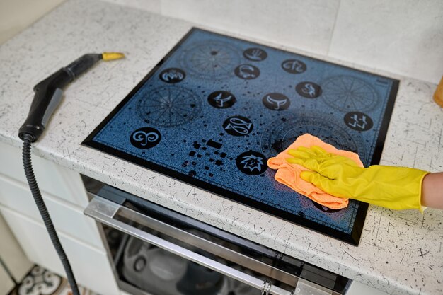 Photo wiping the electric stove with a rag from dirt dust and grease the girl does the cleaning of the kitchen cleaning with a steam generator