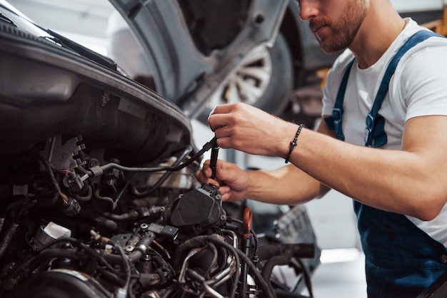 クラッチ用ワイヤーを手に。自動車サロンで働く青い制服を着た社員。