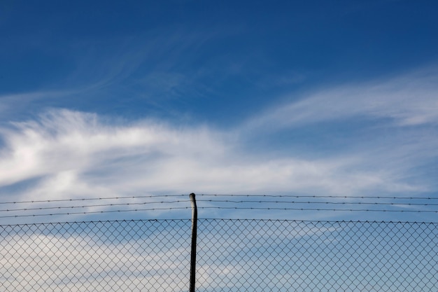 雲と青い空とワイヤーフェンス