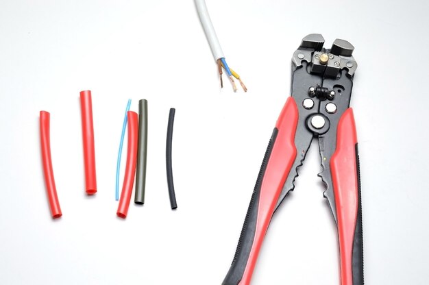 Photo wire stripper, shielded three-core wire and heat shrink tubing on a white background. close-up