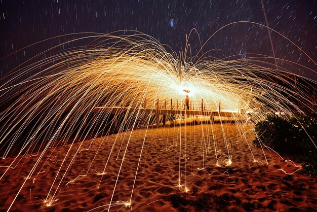 Wire wool at beach against sky during night