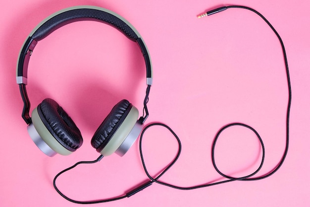 Wired headphones in khaki on a pink background.