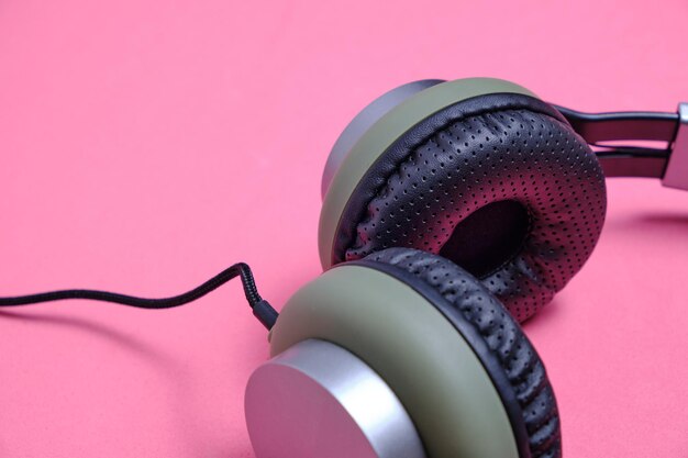 Wired headphones in khaki on a pink background.