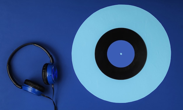 Wired headphones with a vinyl record on blue background. retro\
style, dj. top view, minimalistic music concept.