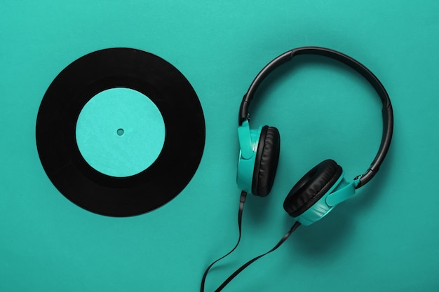 Wired headphones with a vinyl record on blue background. Retro style, DJ. Top view, minimalistic music concept.