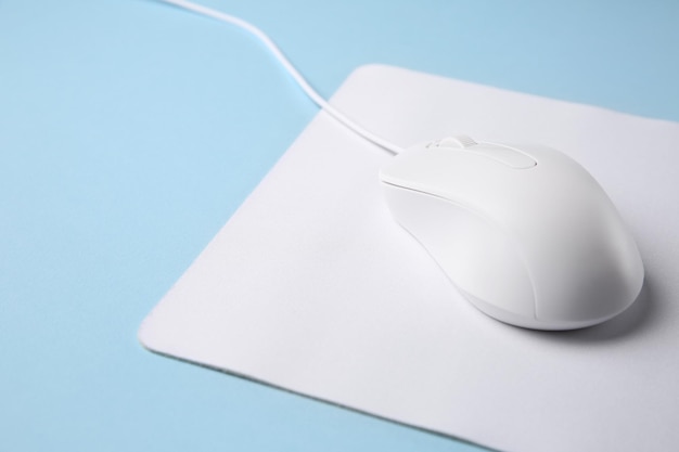 浅い青い背景のクローズアップでマウスパッドを搭載したワイヤードマウス