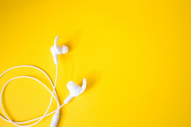 Photo wired white headphones on a yellow wall