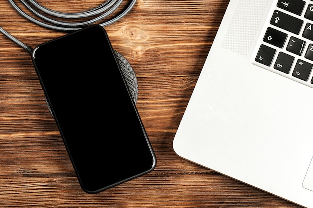 Wireless charging lies next to the computer on a stylish wooden table.