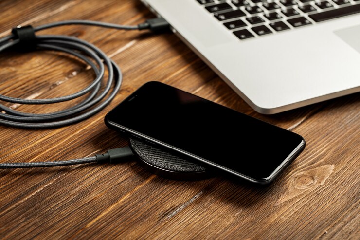 Photo wireless charging lies next to the computer on a stylish wooden table.