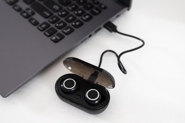 Wireless headphones connected to charge to a laptop