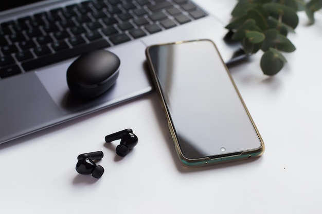 Photo wireless headphones, mobile phone and laptop on the desktop