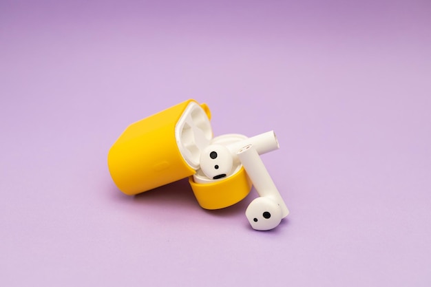 Wireless headphones in a yellow case on a purple background