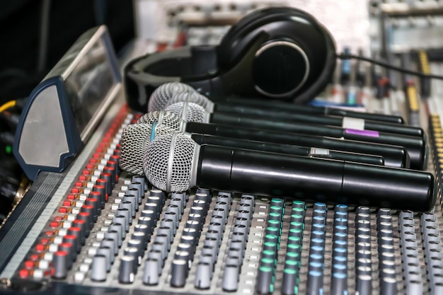 Фото Беспроводный микрофон и наушники на панели управления звукомешателем звукомешателя эквалайзера