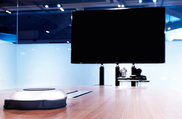 Wireless microphone portable on table with blank screen television in meeting room