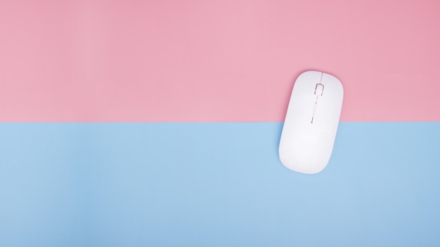 Wireless mouse for computer and laptop on blue and pink background. top view. copy space.