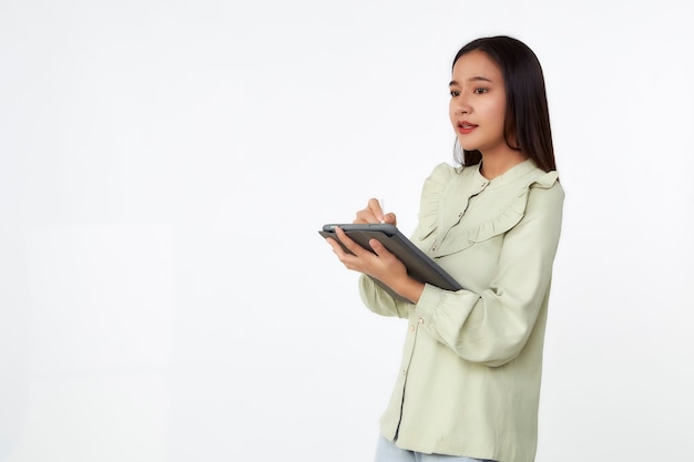 Wireless technology. Beautiful young Asian woman holding digital tablet and looking at camera with smile while standing isolated on white background.