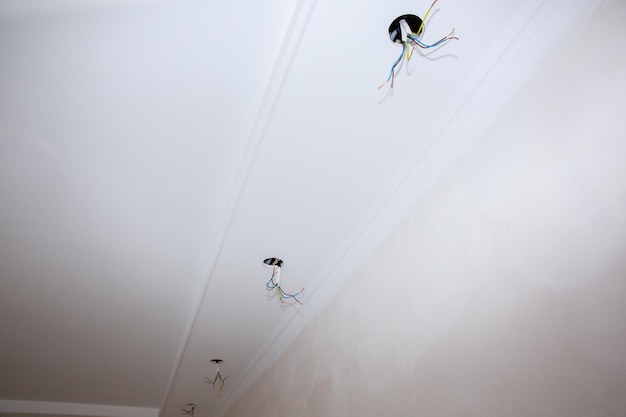 Wires and holes for light bulb in the ceiling Electricity maintenance repair works in the flat Restoration indoors