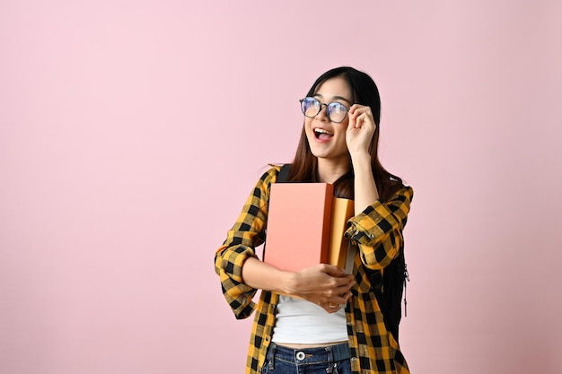 Wise Asian female college student touching her glasses showing amazed facial expression