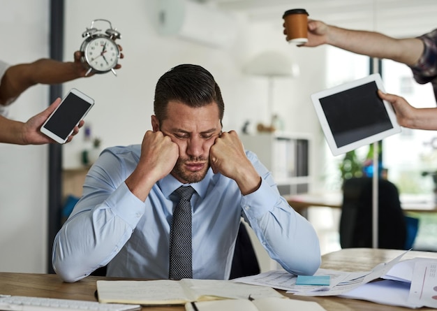 Wishing his deadlines away Shot of a stressed out businessman surrounded by demanding colleagues in an office