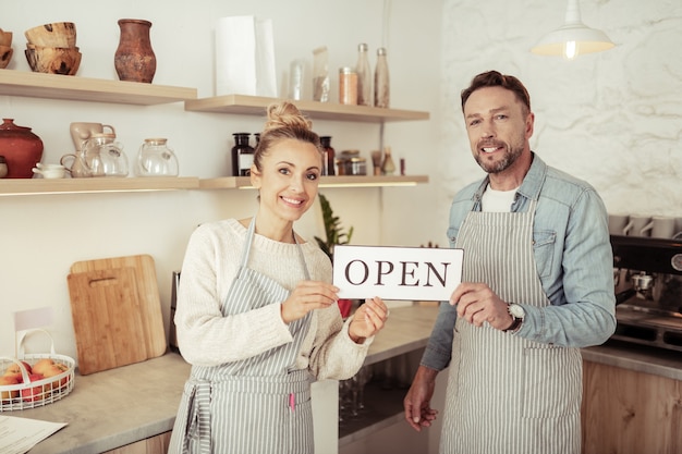 Auguri di benvenuto. i proprietari sorridenti di una bella caffetteria di famiglia salutano i loro primi visitatori.