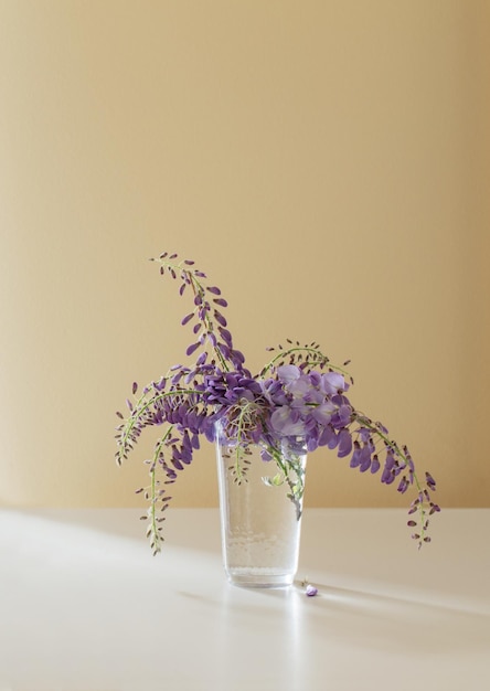 Цветы глицинии в стеклянной вазе в помещении