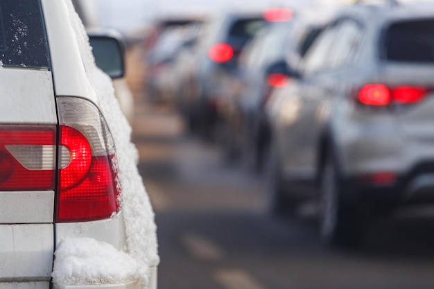 Wit autoachterlicht met sneeuw en wazig verkeer op de achtergrond op winterdag