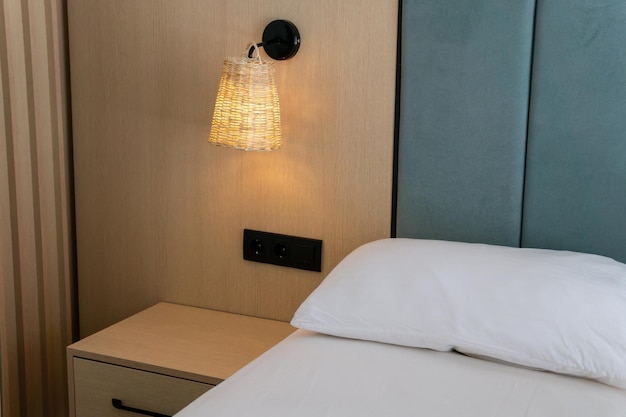 Wit bed naast het houten nachtkastje en een verlichte lamp concept hotels decoratie en meubels