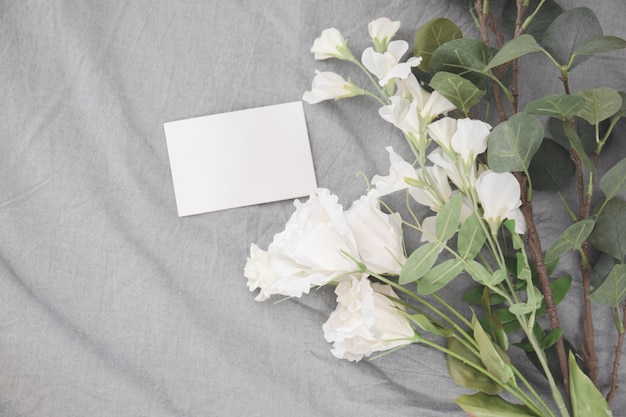 Foto wit bloemen romantisch boeket en de lege stapel van de beeldverhaalkaart op bed.
