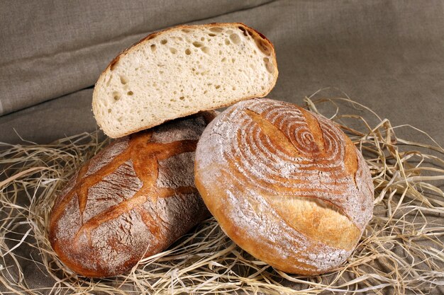 Wit brood twee verschillende vormen liggend in het stro op grijs linnen tafelkleed