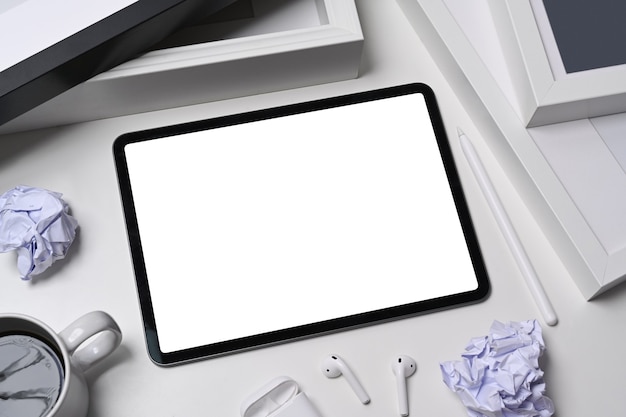 Wit bureau met digitale tablet, verfrommeld papier en koffiekopje.