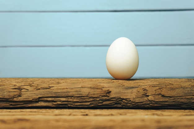 Wit ei op een oude eiken houten tafel blauwe achtergrond