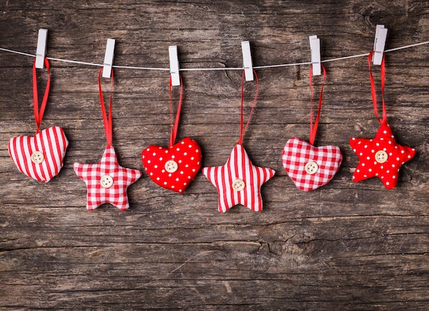 Wit en rood genaaid kerstdecor bevestigd aan het touw, over houten achtergrond