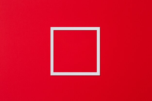 Wit frame in de vorm van een vierkant op een rode achtergrond minimalisme plat lag kopieerruimte
