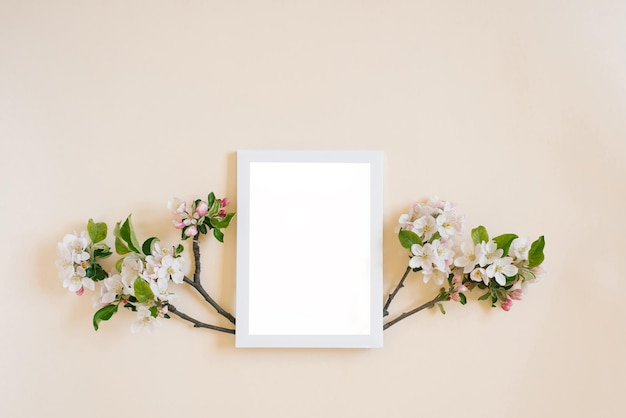 Wit frame met kopieerruimte op een beige achtergrond omringd door takken met witte appelbloemen