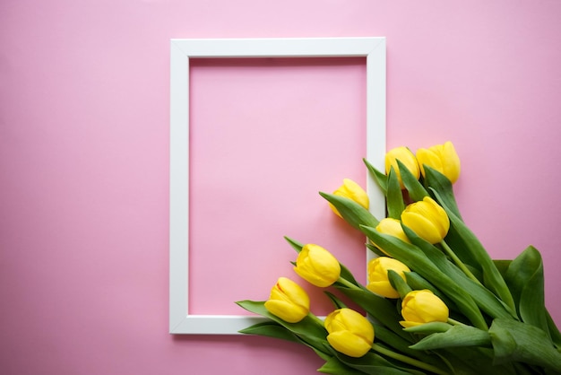 Wit frame met op de hoeken tulpen op een roze achtergrond met een lege ruimte