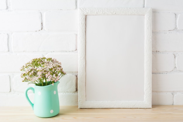 Wit frame mockup met zachtroze bloemen in de buurt van zichtbare bakstenen