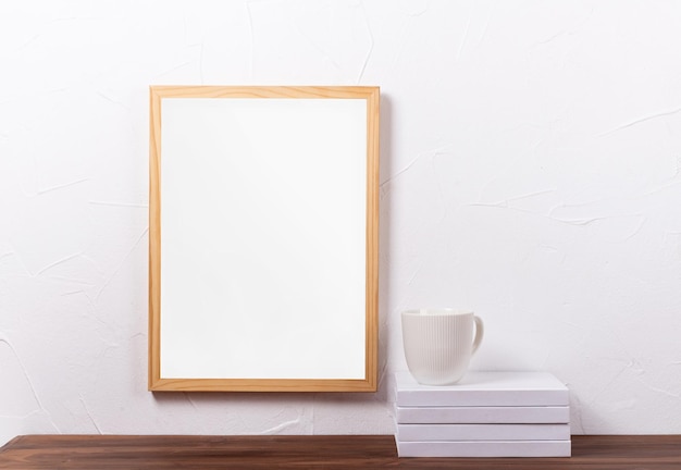 Wit framemodel dat aan de muur hangt met een stapel boeken en een koffiekopje