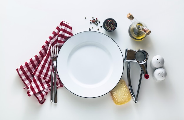 Wit geëmailleerde lege plaat op tafel met een rood geruit servet en Parmezaanse kaas