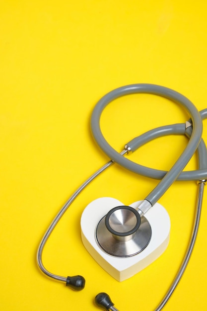 Wit hart en stethoscoop op gele achtergrond Medisch onderzoek voor hart- en vaatziekten