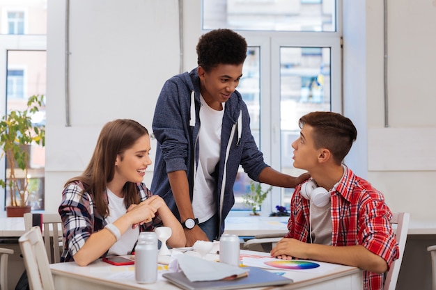 Wit horloge. Knappe student die een wit polshorloge draagt dat naar zijn collega's komt die in de bibliotheek studeren