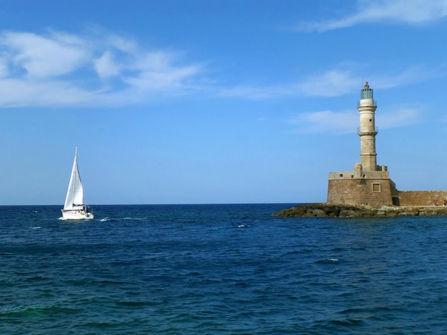 Wit jacht zeilen in de buurt van historische vuurtoren in de oude Venetiaanse haven in Chania op het eiland Kreta, Griekenland