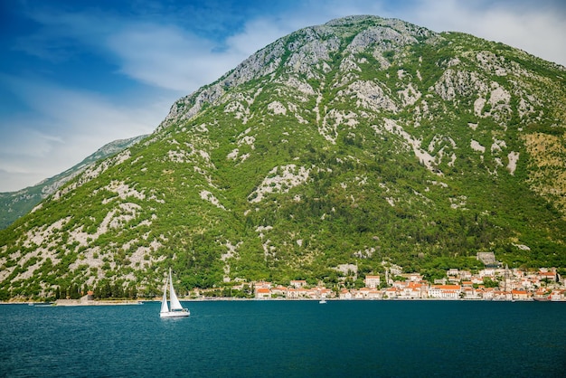 Wit jacht zeilen langs de historische stad Perast aan de beroemde baai van Kotor